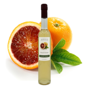 a bottle of balsamic in front of a sliced and whole blood orange