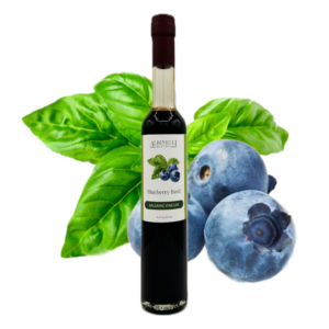 a bottle of balsamic vinegar in front of basil and blueberry