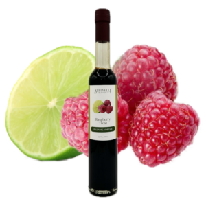 bottle of balsamic in front of a sliced lime and raspberry cluster